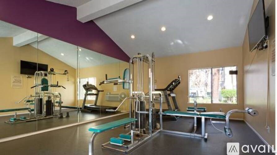 A gym with a variety of equipment including treadmills, weights, and exercise machines.