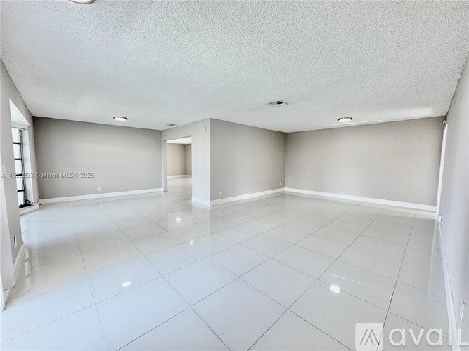 A spacious room with white tiled flooring and white walls.