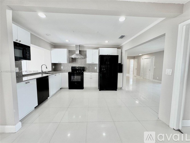 A spacious kitchen with black and white appliances and white cabinets.