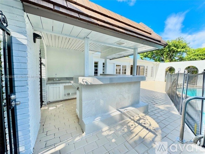 A white house with a brown roof and a black gate.
