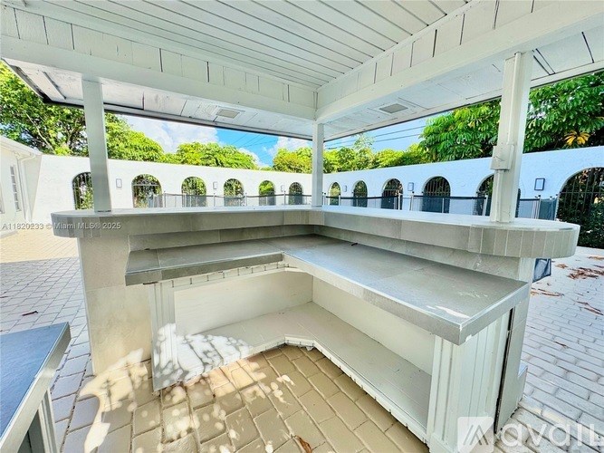 A white outdoor kitchen area with a bench and a table.
