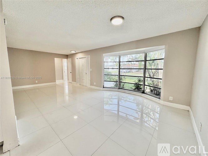 A spacious empty room with a large window and sliding glass door.