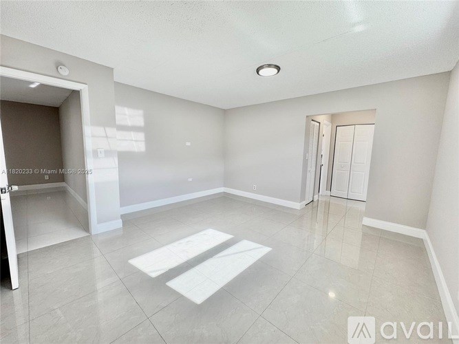 A spacious room with a white floor and walls, and a ceiling light.