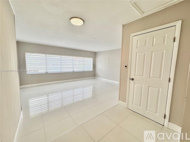 A white door is on the right side of a room with a window and a ceiling light.