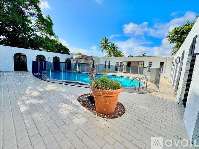 A large orange pot sits in the middle of a brick patio.