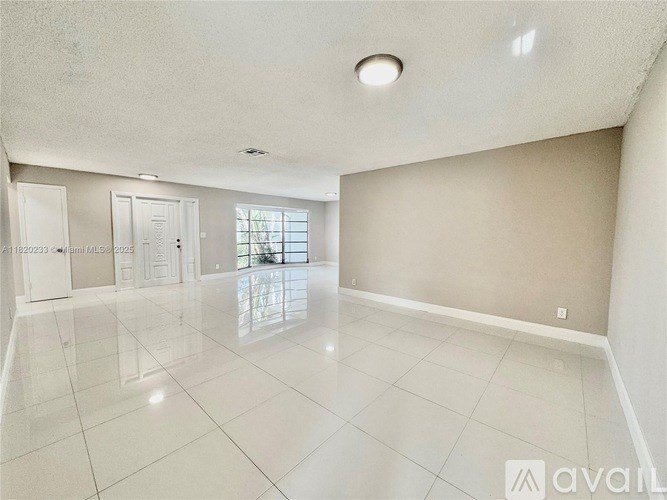 A spacious room with white tile flooring and a large window.
