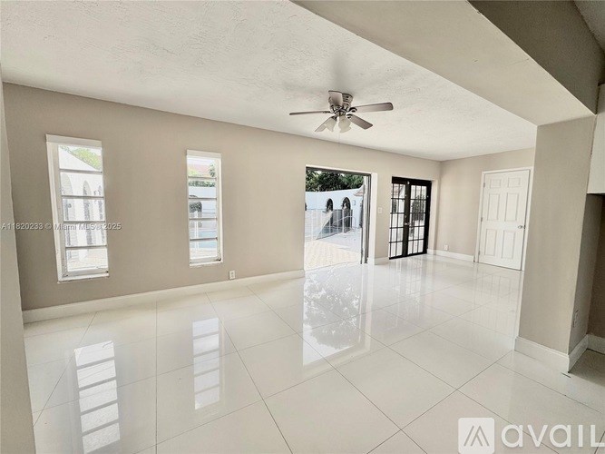 A spacious room with a ceiling fan and large windows.