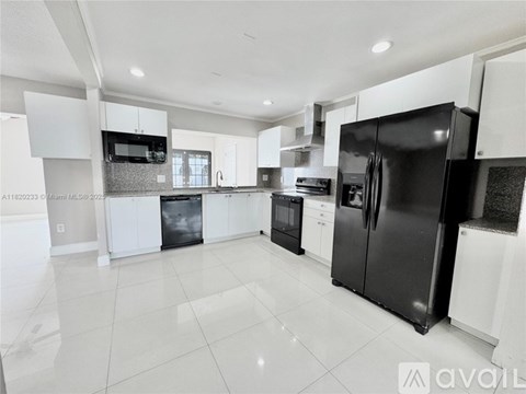 A modern kitchen with black and white appliances and cabinets.