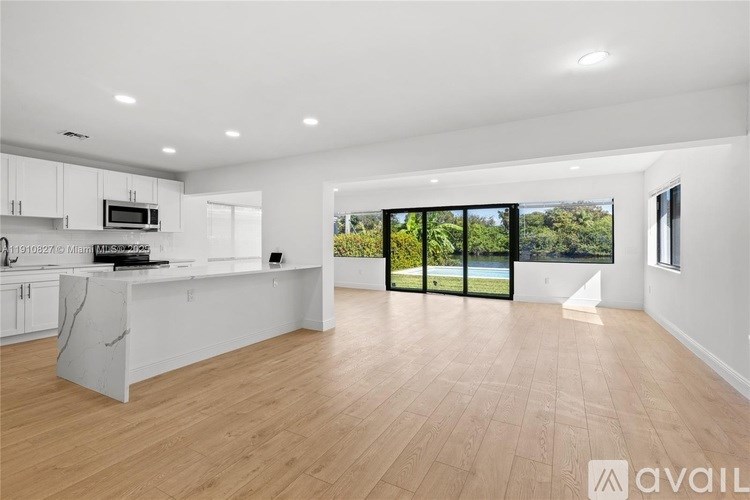 A spacious kitchen with wooden flooring and white cabinets.