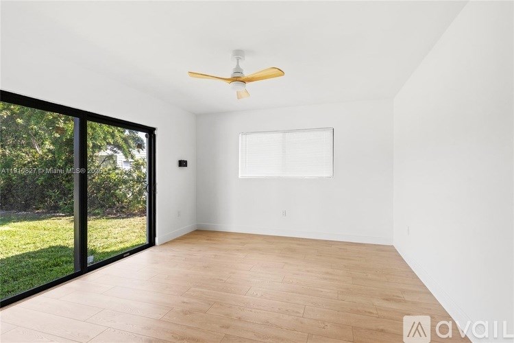 A room with a ceiling fan and sliding glass doors.