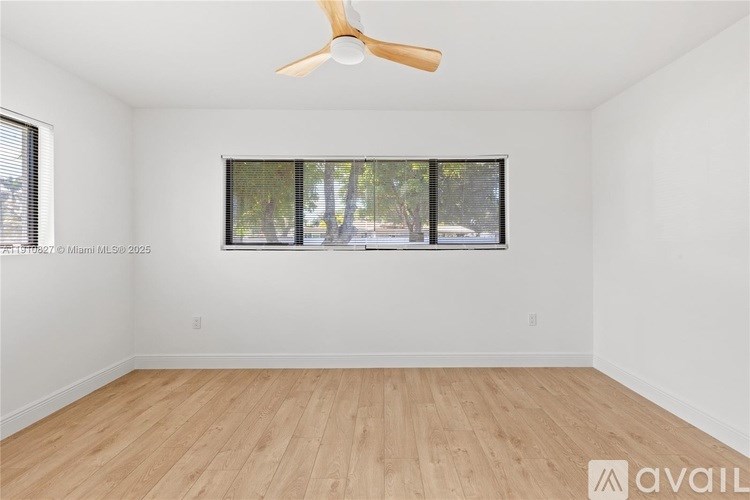 A room with a ceiling fan and a window with blinds.