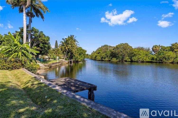 A serene lake surrounded by lush greenery and palm trees under a clear blue sky.