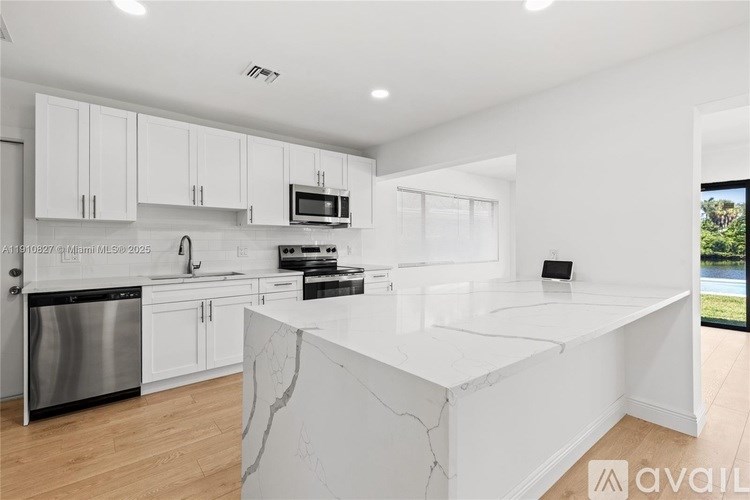 A modern kitchen with a large island and stainless steel appliances.