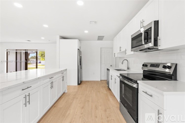 A kitchen with white cabinets and black appliances.