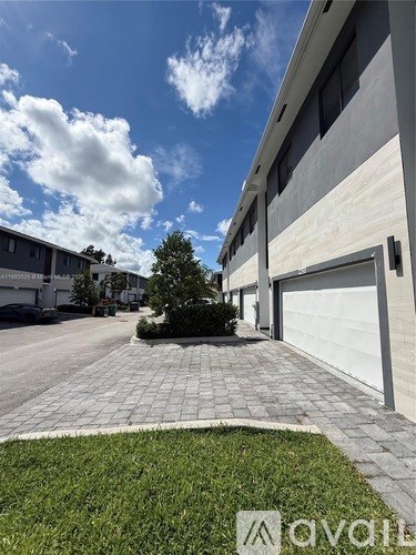 A modern house with a driveway and a tree in the front yard.