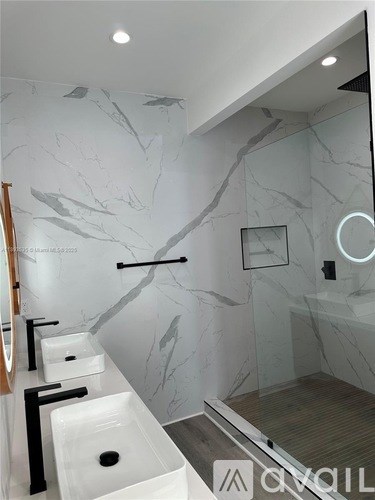 A modern bathroom with marble walls and a wooden floor.