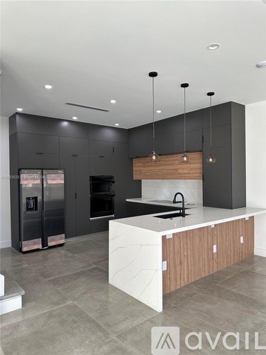 A modern kitchen with a white island and dark cabinets.