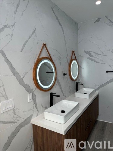 A bathroom with marble walls and two round mirrors.