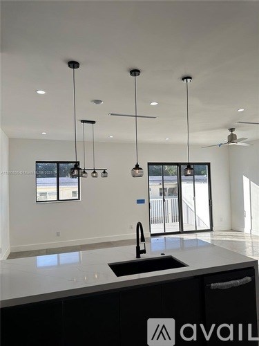 A modern kitchen with a sink and pendant lights.