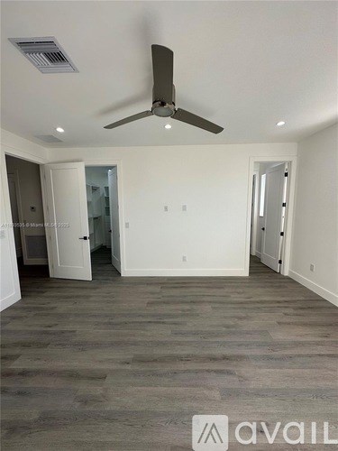 A room with a ceiling fan and wooden flooring.