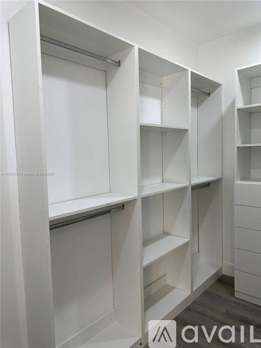 A white walk-in closet with shelves and hanging space.