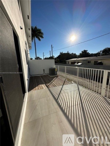 A sunny day on a balcony with a view of the sky and palm trees.