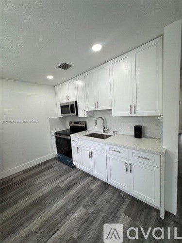 A kitchen with white cabinets and a grey floor.