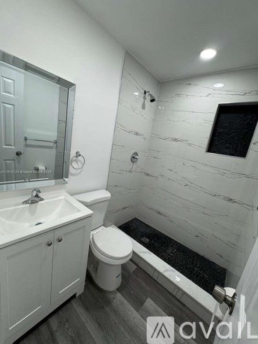 A white bathroom with a toilet, sink, and mirror.