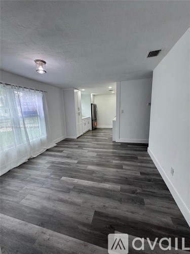 A long hallway with wood flooring and white walls.
