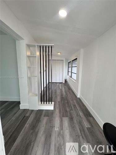 A long hallway with wood floors and white walls.