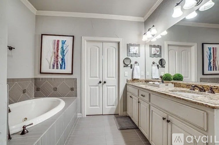 A bathroom with a tub, sink, and mirror.