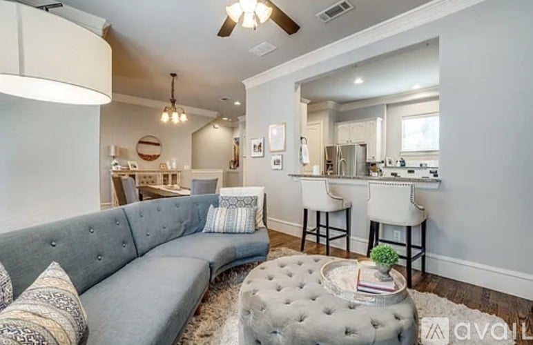 A living room with a grey couch and a round ottoman in the center.