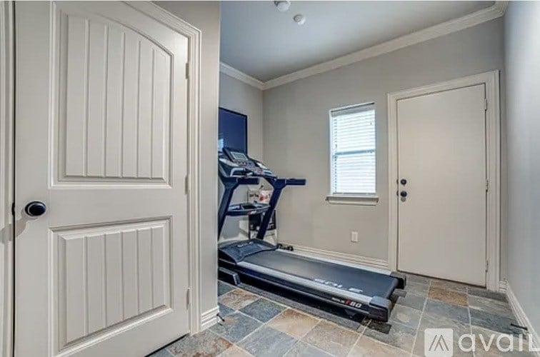 A treadmill is in a room with a door and a window.