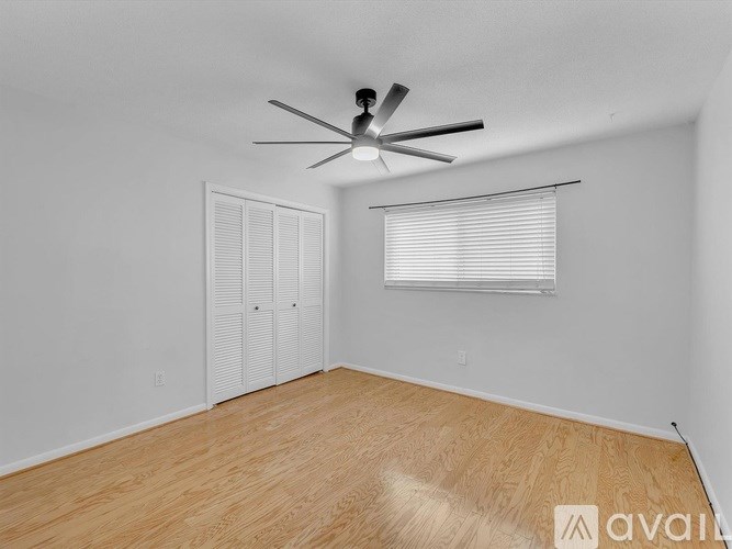 A room with a ceiling fan and a window with blinds.