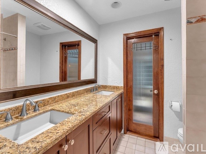 A bathroom with granite countertops and a wooden door.