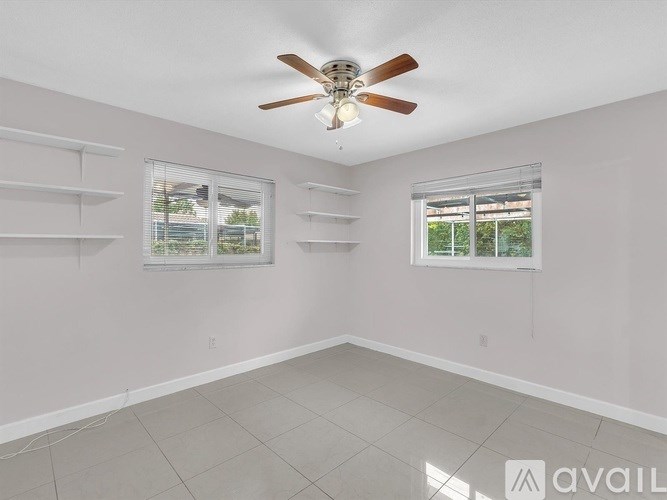 A room with a ceiling fan and two windows.
