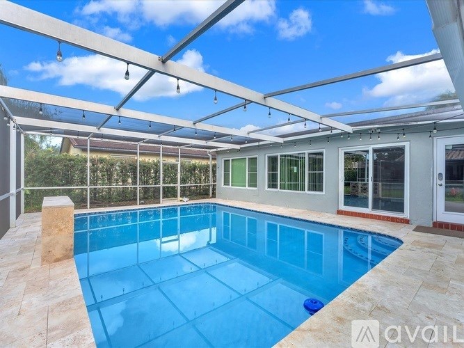 A swimming pool under a glass roof with a tiled floor.