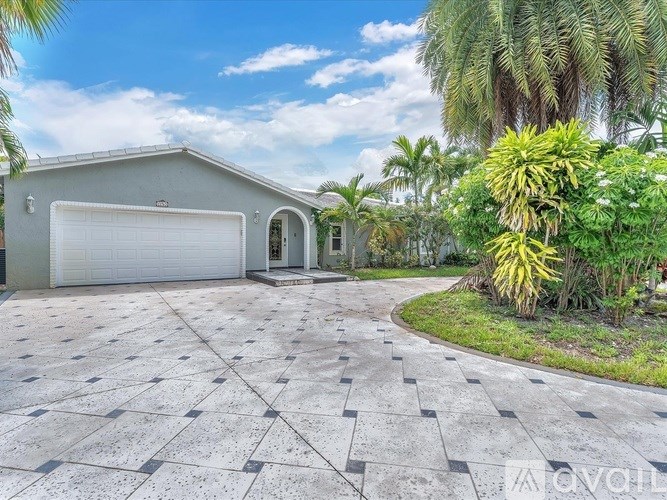 A house with a driveway and palm trees in front.