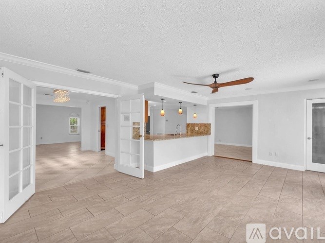 A spacious room with a ceiling fan and lighting fixtures.