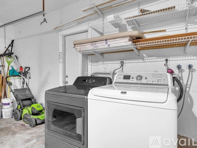 A white washing machine is in a laundry room with a dryer and a vacuum cleaner.