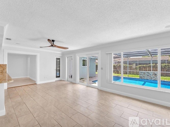 A spacious room with a fan and a pool visible through the windows.
