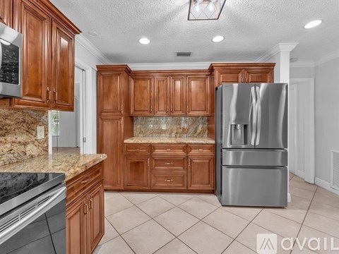 A kitchen with brown cabinets and a stainless steel refrigerator.
