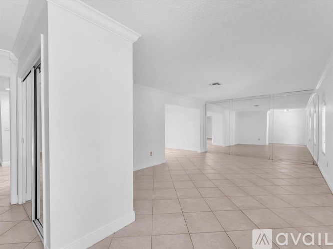 A spacious, empty room with white walls and tiled flooring.