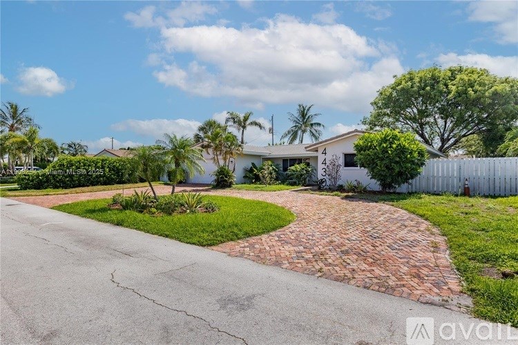 A house with a white fence and a driveway with a brick border.