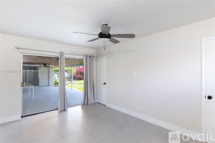 A room with a ceiling fan and sliding glass doors leading to a garden.