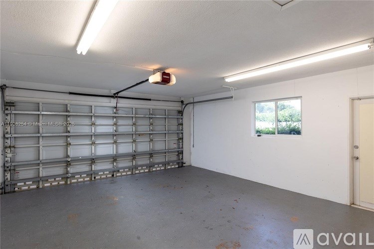 A large empty garage with a roll-up door and a window.
