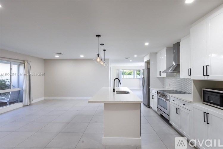 A modern kitchen with white cabinets and a large island.