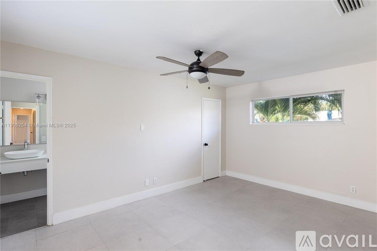 A spacious room with a ceiling fan and a door leading to another room.