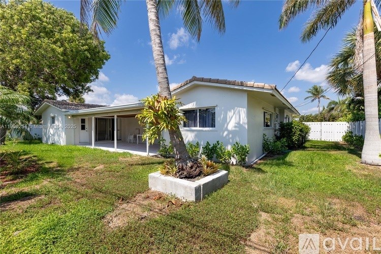 A white house with a palm tree in front.