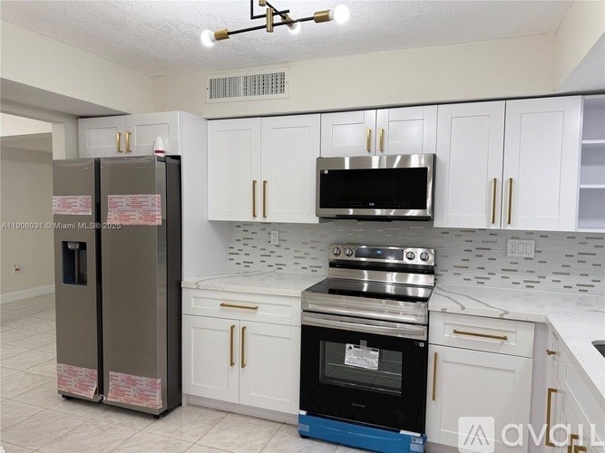 A kitchen with white cabinets and a black fridge.